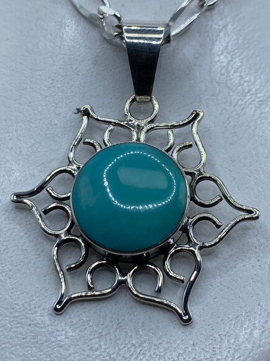 Dije de plata .950 con turquesa azul cielo engastada en marco ornamental de Taxco