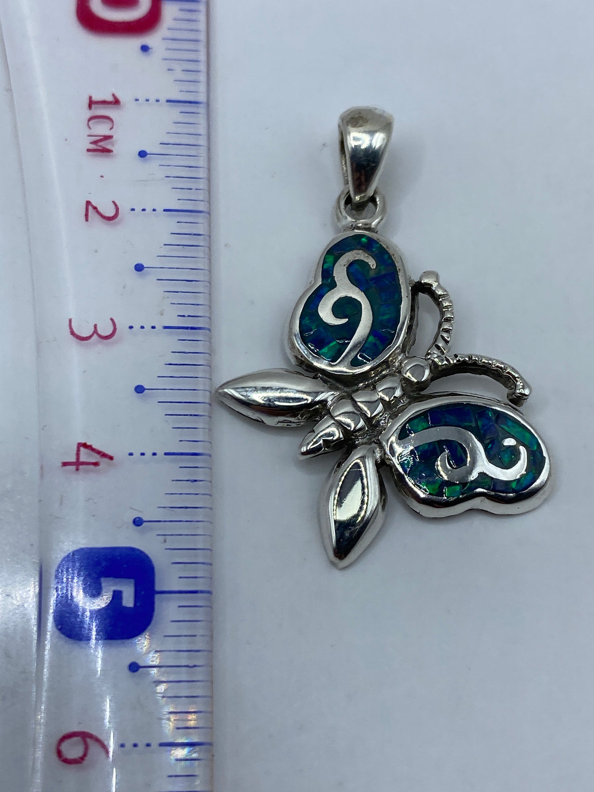 Dije de 4.5 cm sobre escala de medidas, junto al sello de autenticidad