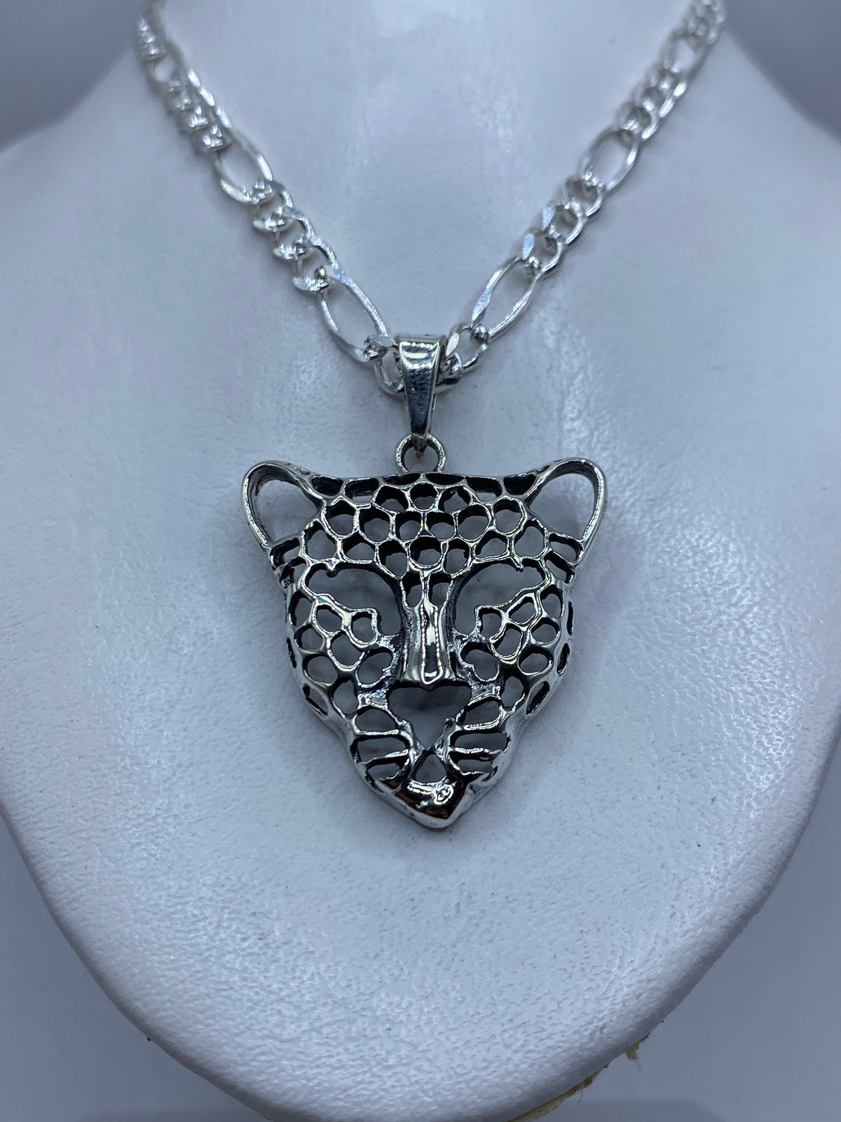 Dije de jaguar calado sobre una cadena de plata figaro, colgando al cuello