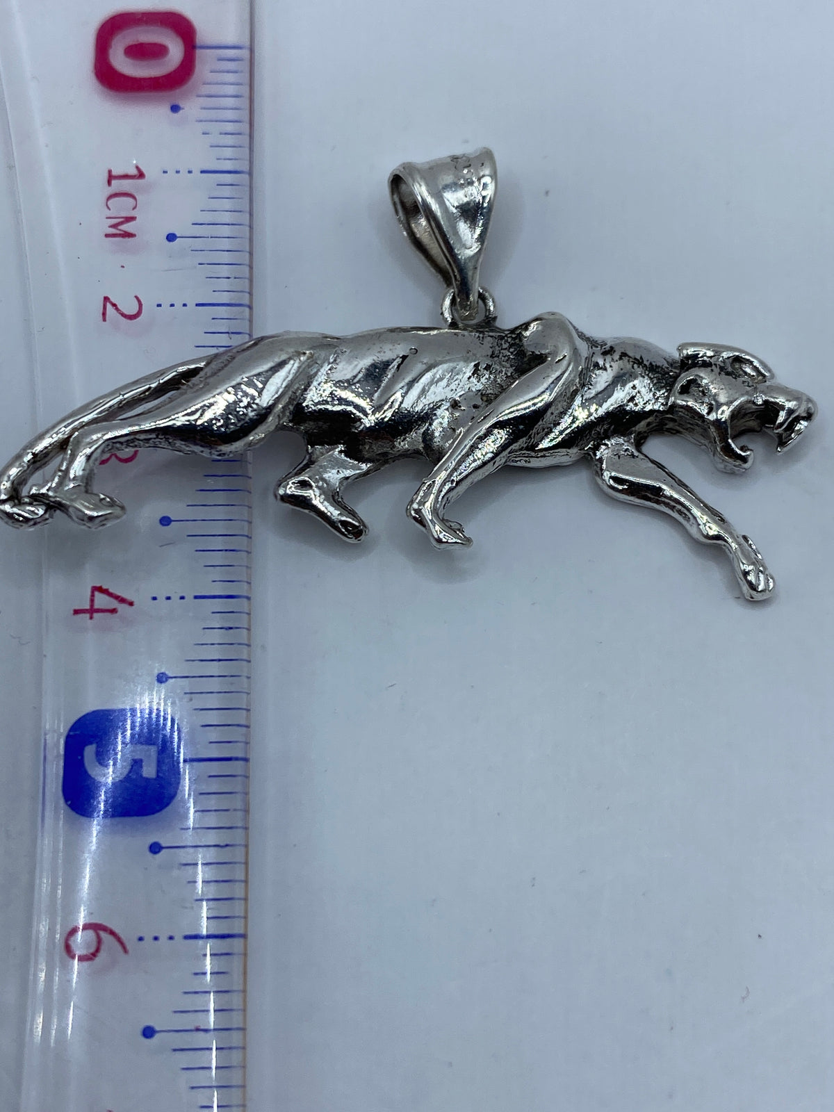 Dije jaguar de plata en una balanza de precisión, pesando 6.8 gramos