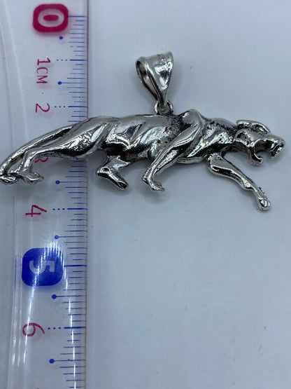 Dije jaguar de plata en una balanza de precisión, pesando 6.8 gramos