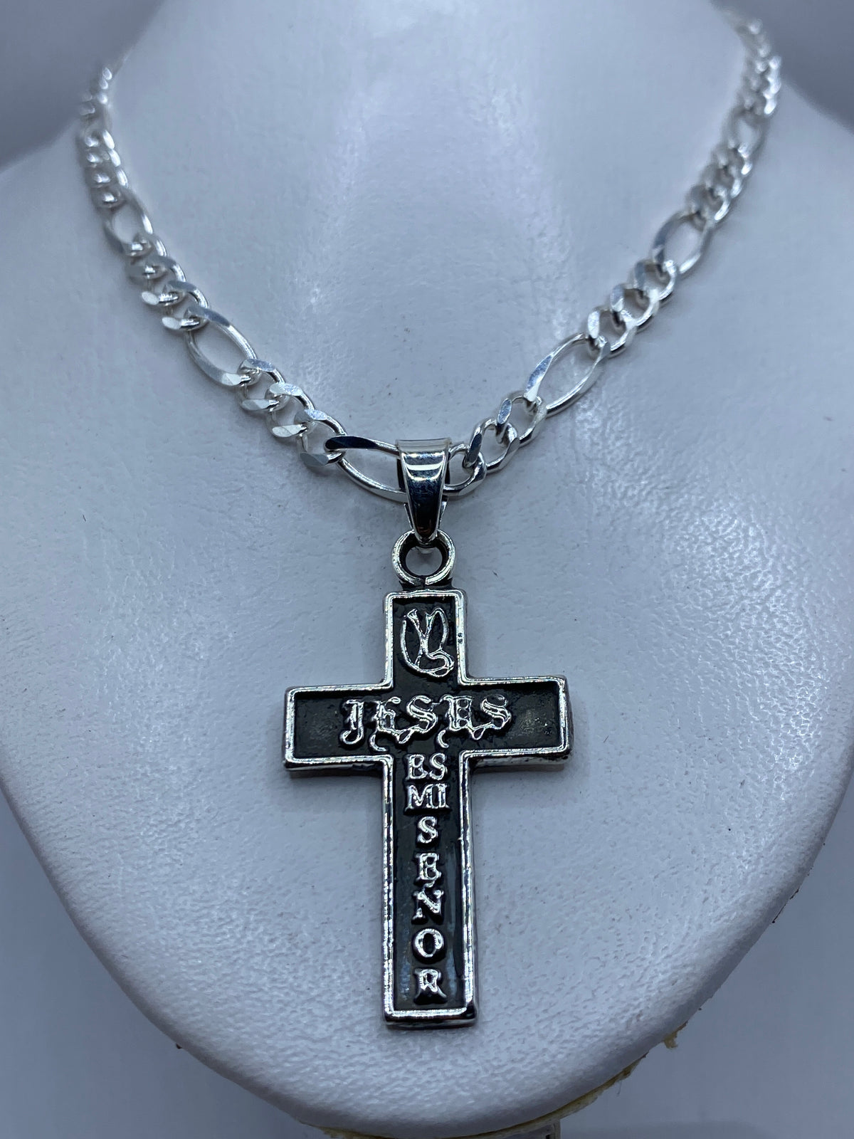 Vista frontal de la cruz de plata, diseño religioso con letras grabadas