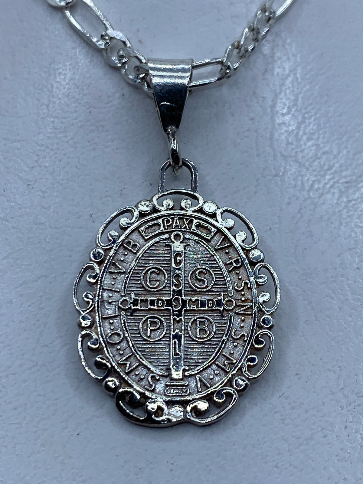 Reverso del medallón de San Benito mostrando cruz y símbolos de protección