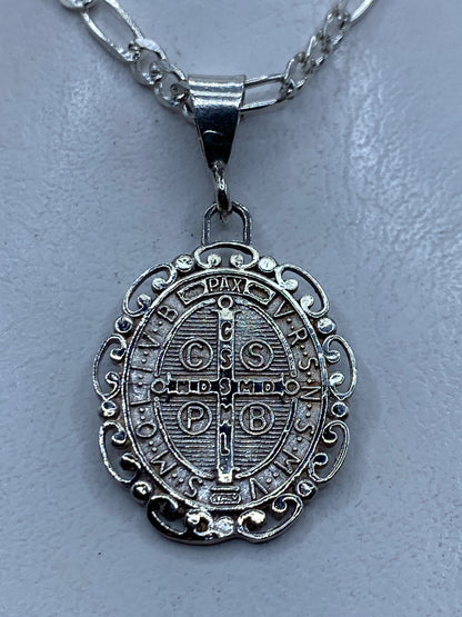 Reverso del medallón de San Benito mostrando cruz y símbolos de protección