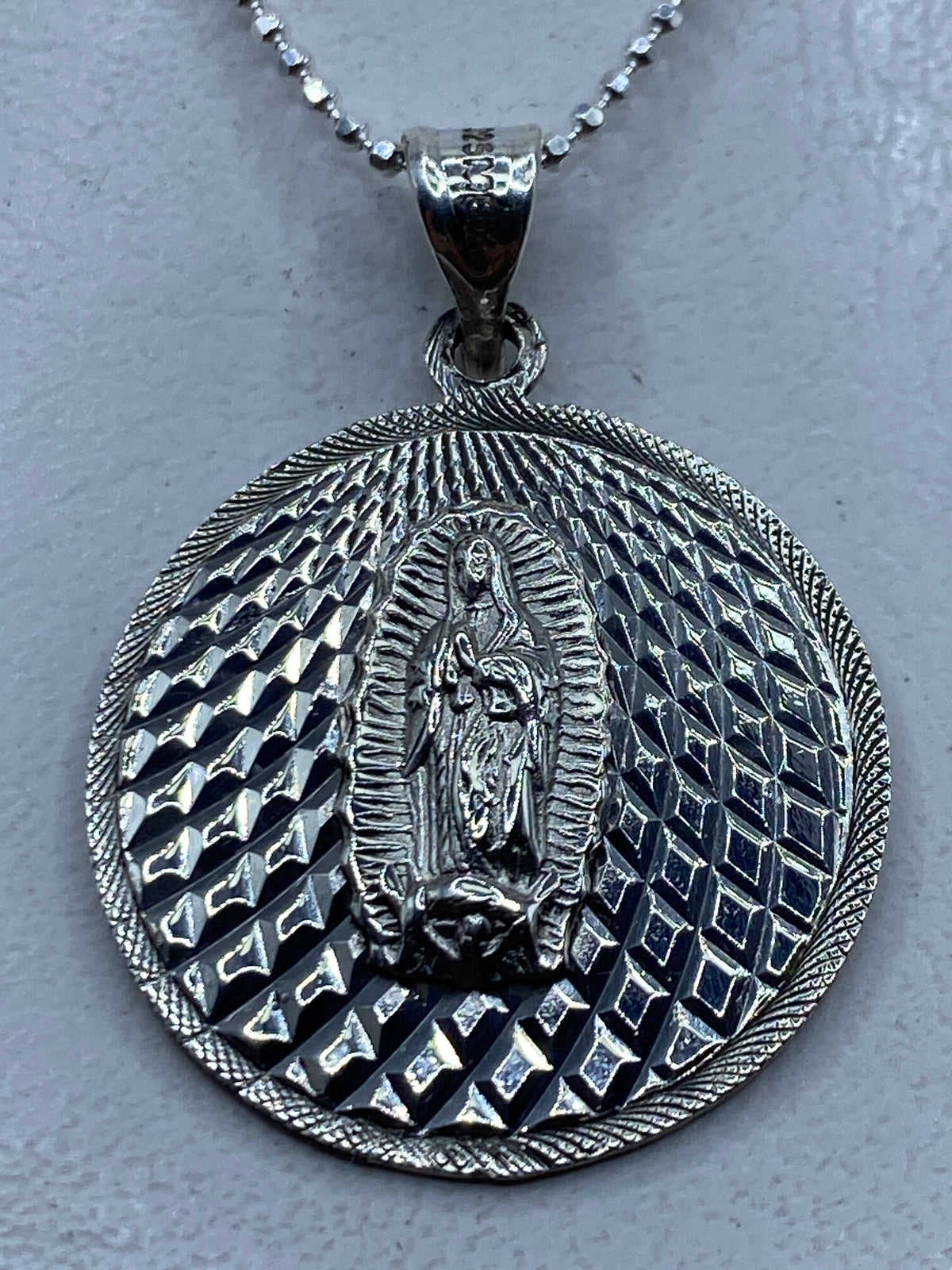Dije de plata .925 con Virgen de Guadalupe en relieve repujado, colgando de cadena de bolas