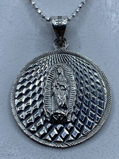 Dije de plata .925 con Virgen de Guadalupe en relieve repujado, colgando de cadena de bolas
