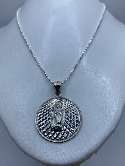 Detalle frontal del dije mostrando el repujado de la Virgen de Guadalupe en mandorla