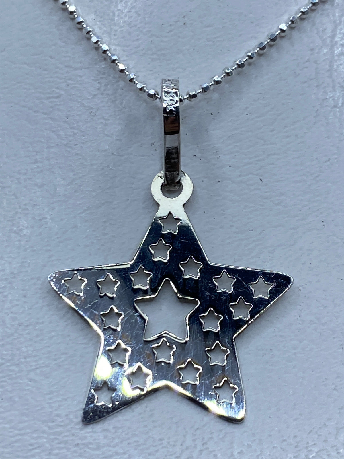 Dije estrella de plata calado de Taxco, 4.2 cm, con pequeñas estrellas cortadas en el interior