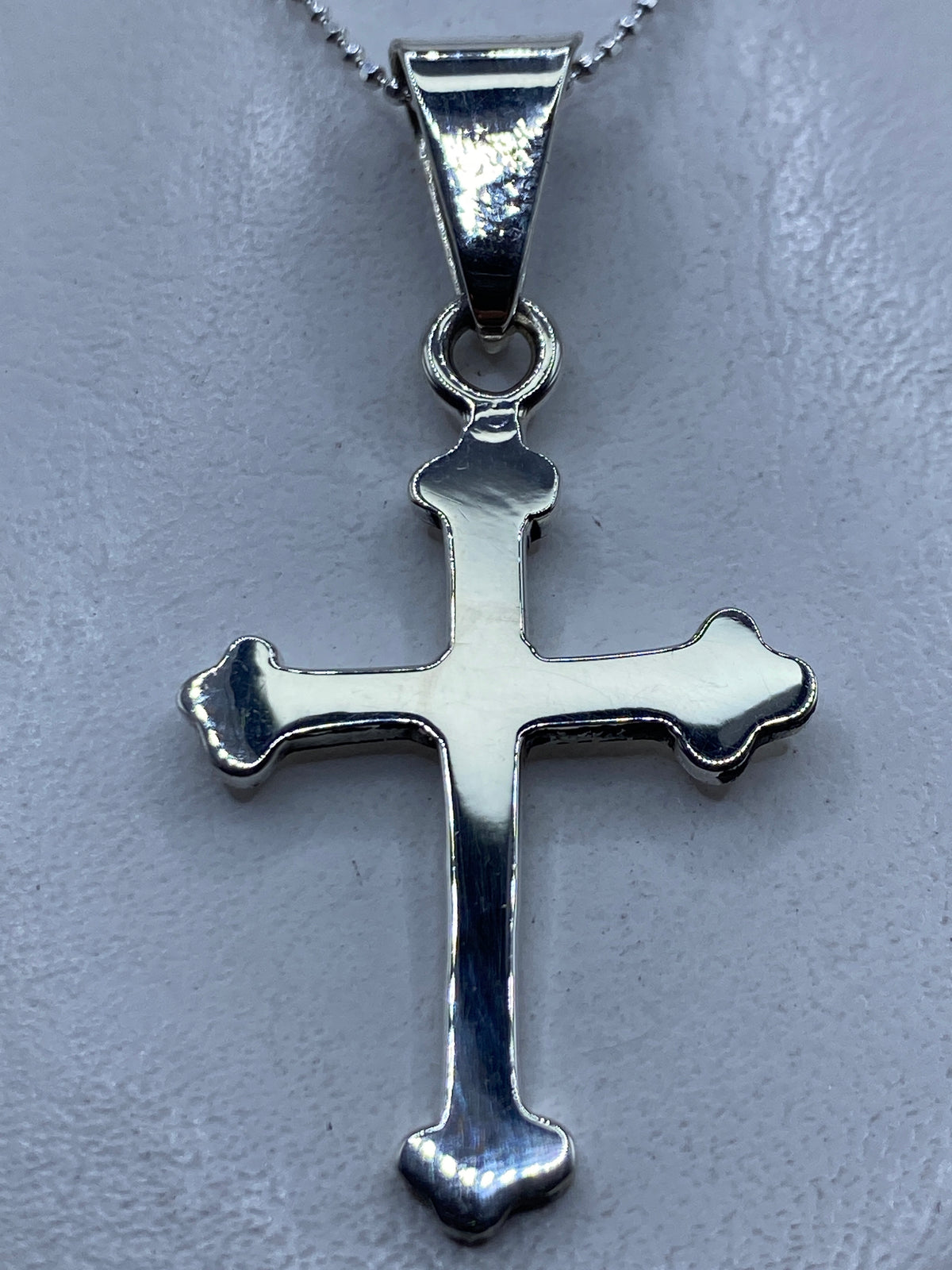 Dije cruz de plata .925 en la mano mostrando el diseño clásico con brazos redondeados