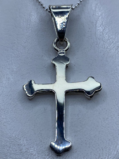 Dije cruz de plata .925 en la mano mostrando el diseño clásico con brazos redondeados