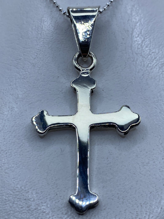 Dije cruz de plata .925 en la mano mostrando el diseño clásico con brazos redondeados