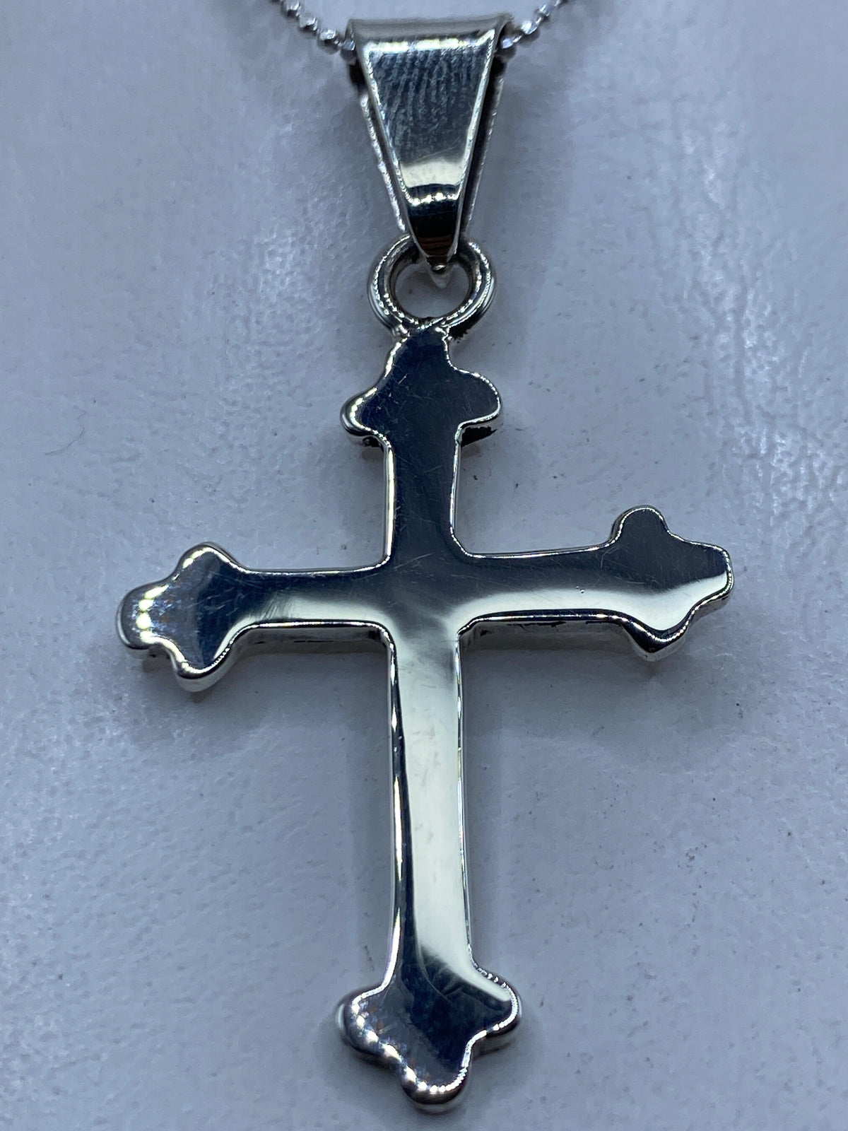 Cruz de plata .925 en calado de Taxco, colgada al pecho sobre una blusa blanca