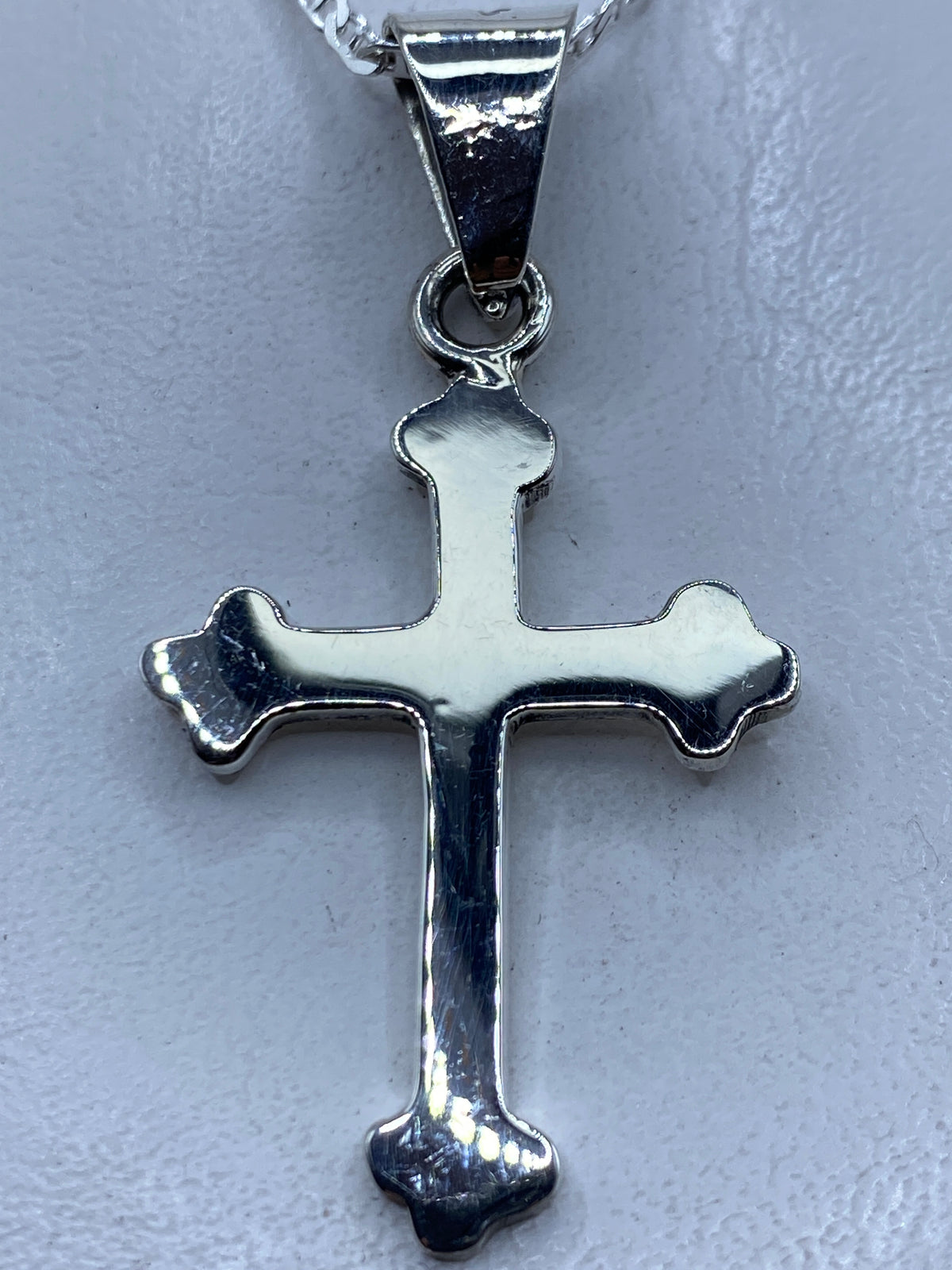 Dije cruz de plata .925 con forma clásica y redondeada, colgante en cadena plateada
