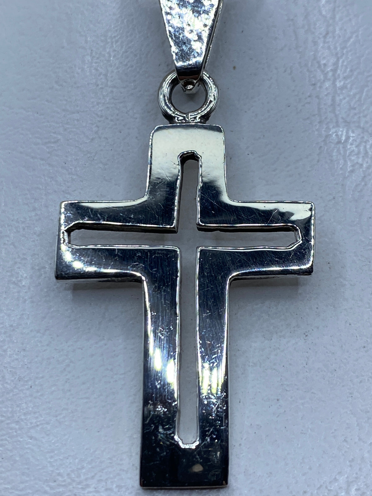 Dije cruz de plata .925 en calado colgando en cadena sobre piel