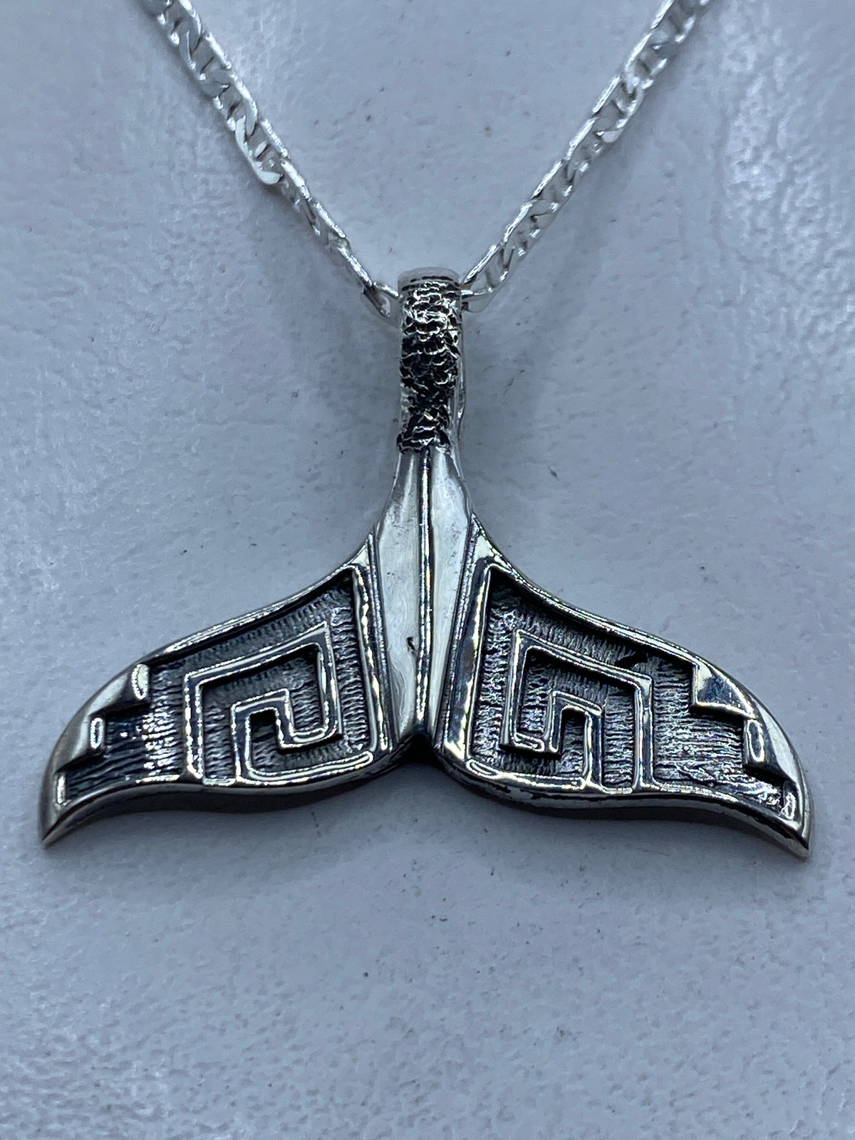 Dije de plata repujado con diseño de cola de ballena prehispánica, largo 3.5 cm