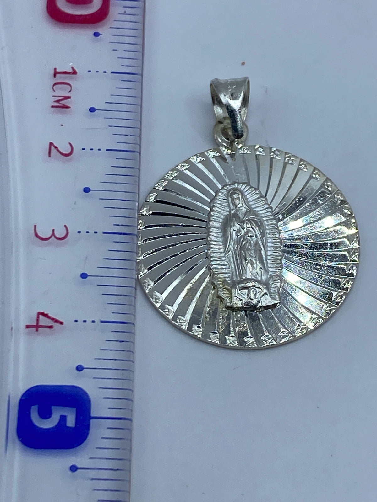 Dije sin cadena sobre fondo blanco mostrando el peso de 3.9 gramos