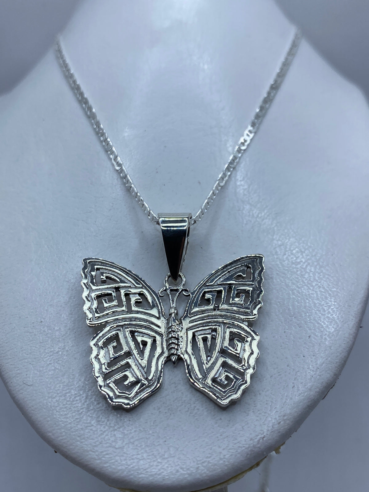 Mariposa de plata con calado artesanal, vista frontal contra fondo blanco