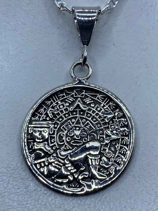 Dije de plata repujado con calendario azteca de frente, sobre cadena de plata
