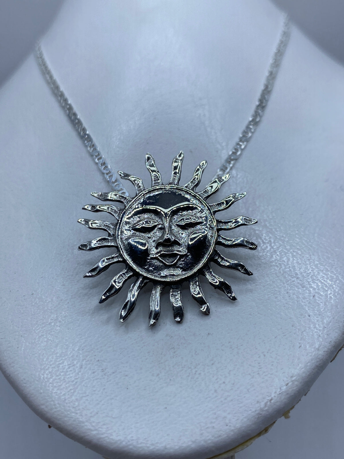 Vista frontal del dije calado con rostros del Sol y Luna, diseño prehispánico
