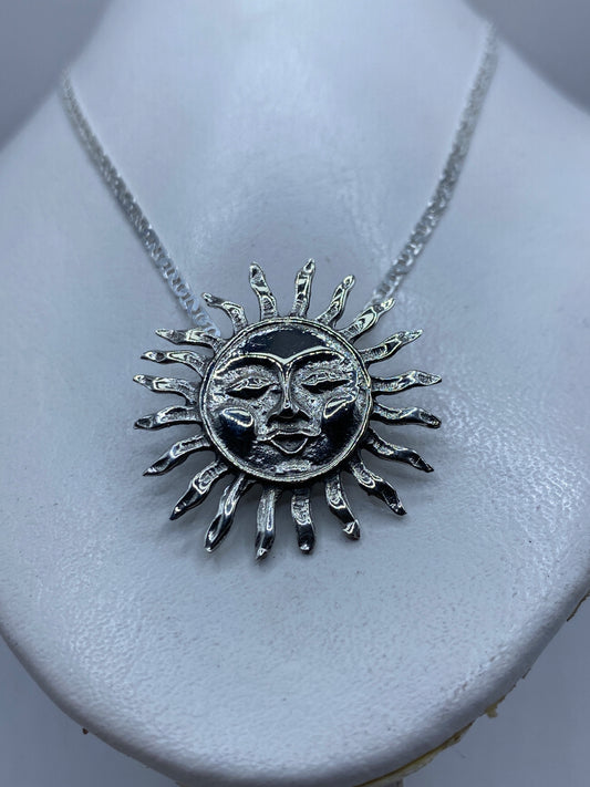 Vista frontal del dije calado con rostros del Sol y Luna, diseño prehispánico
