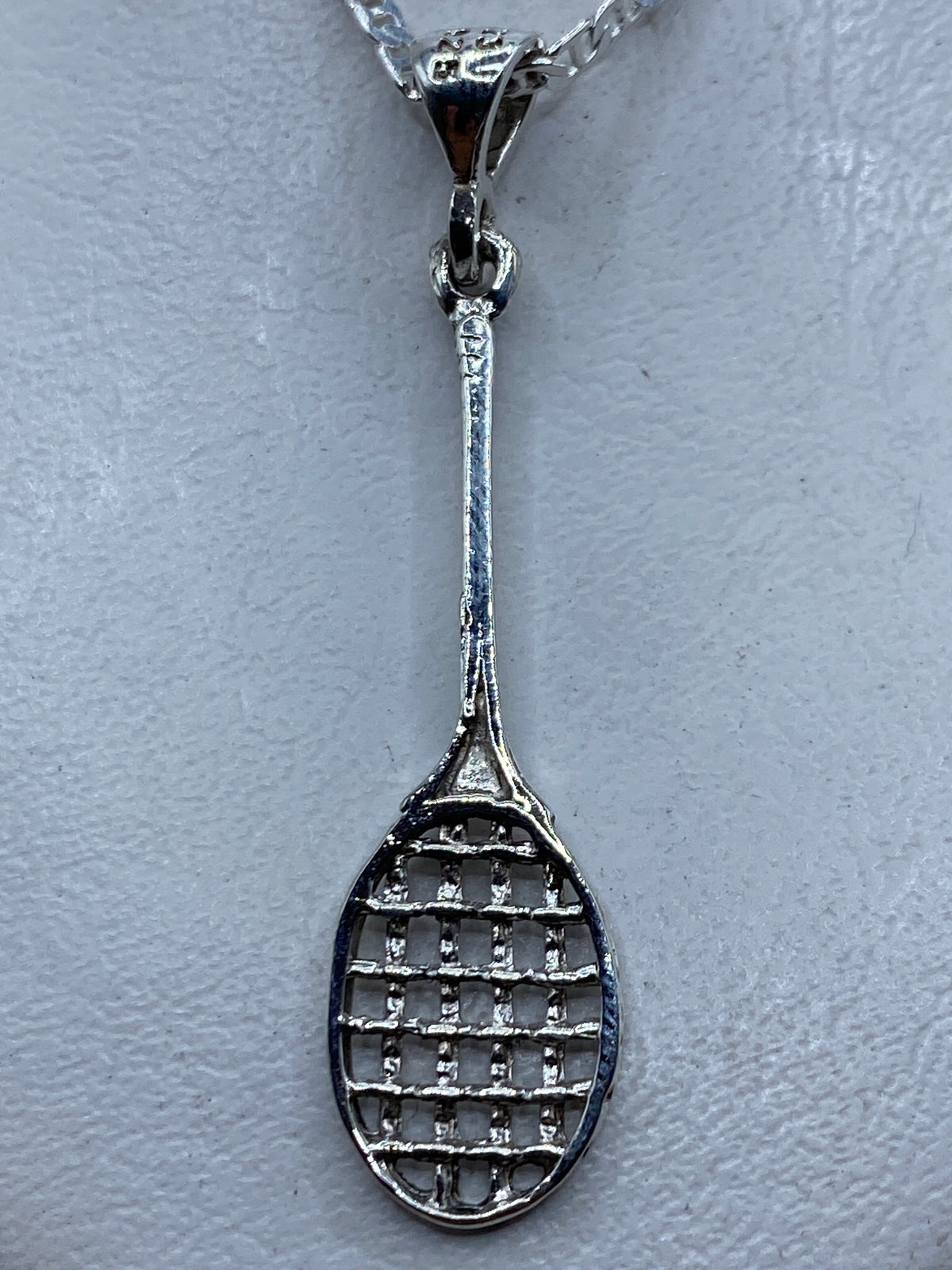 Dije de plata en forma de raqueta de tenis, calado, colgando de una cadena en el cuello