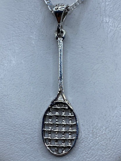 Dije de plata en forma de raqueta de tenis, calado, colgando de una cadena en el cuello