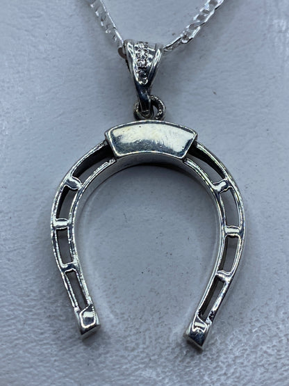 Dije de plata herradura calada de Taxco .925 colgando de cadena plateada