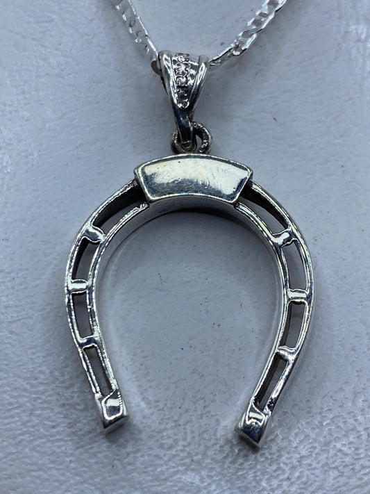 Dije de plata herradura calada de Taxco .925 colgando de cadena plateada