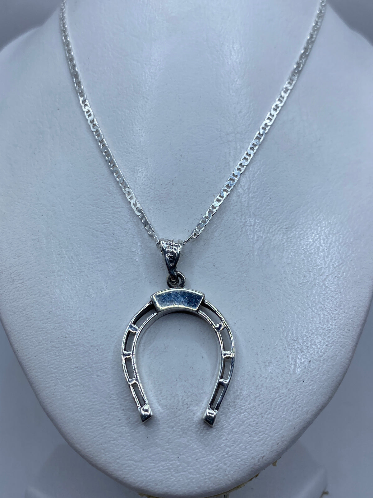 Dije herradura de plata sobre pecho blanco, largo 4.2 cm