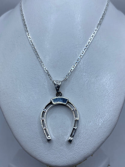 Dije herradura de plata sobre pecho blanco, largo 4.2 cm