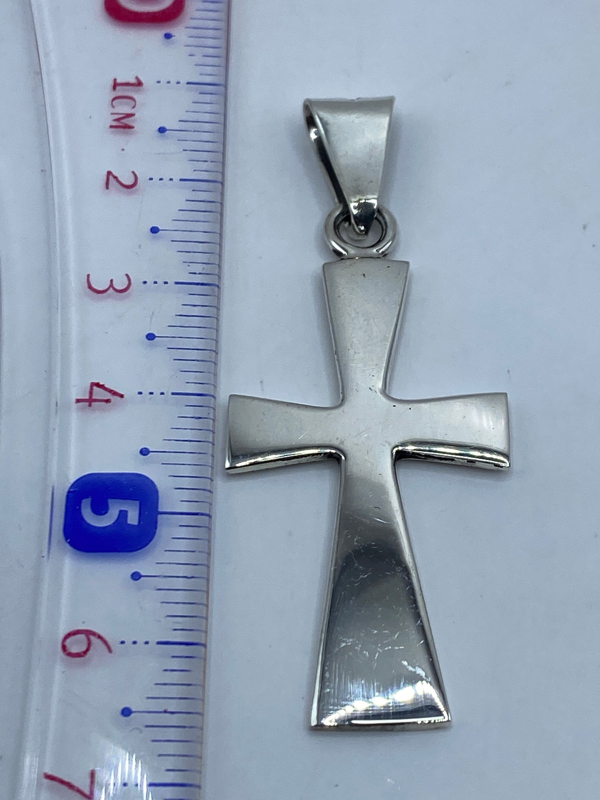Cruz de plata .925 en comparación con una regla de centímetros