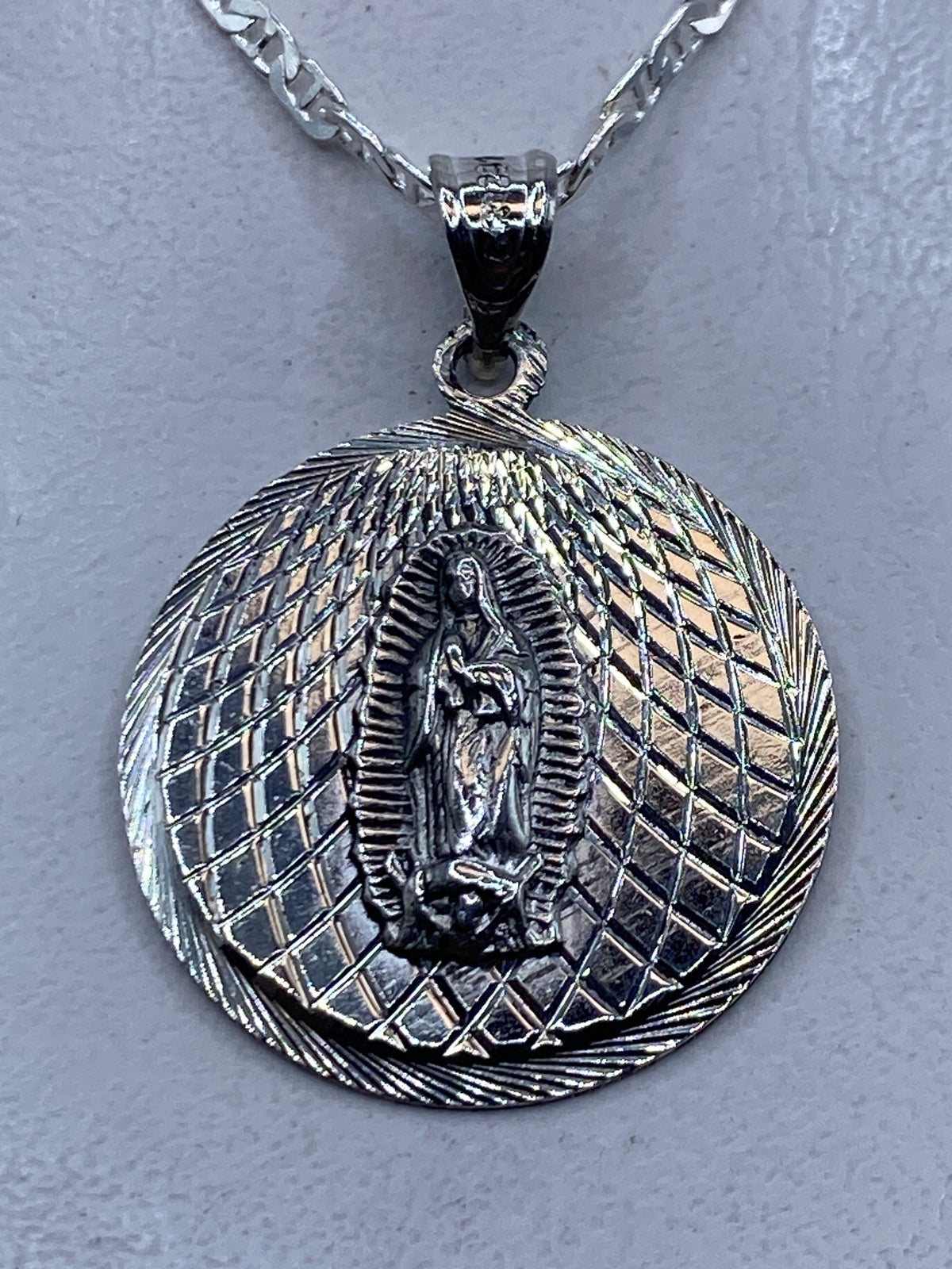 Dije de plata repujado con la Virgen de Guadalupe en relieve, 4 cm, sobre cadena plateada