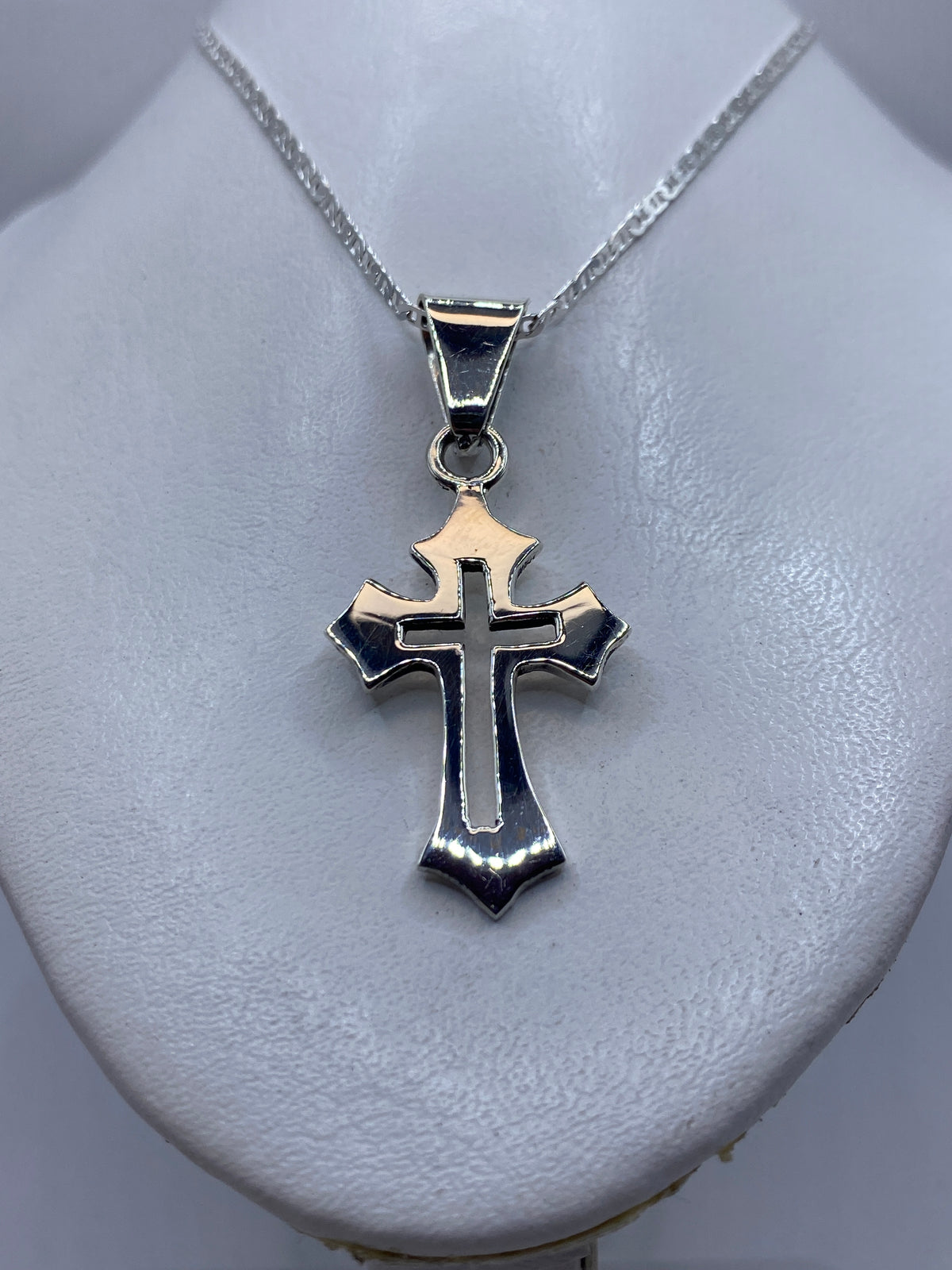 Dije cruz de plata colocado en el pecho de una mujer con cadena de plata