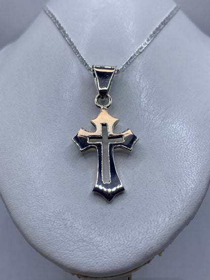Dije cruz de plata colocado en el pecho de una mujer con cadena de plata