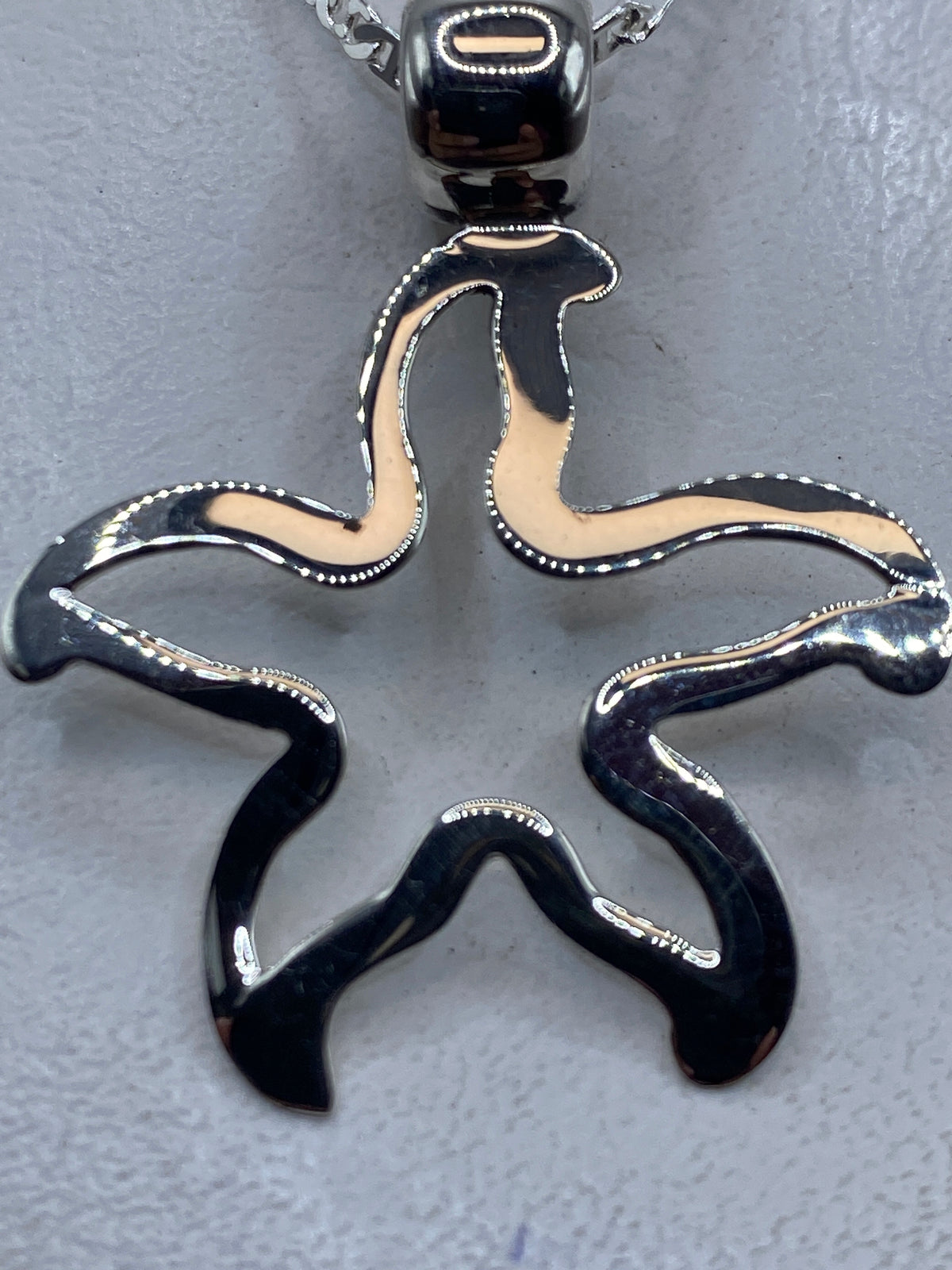 Dije de plata .925 en forma de estrella marina con calado, colgando de cadena de plata