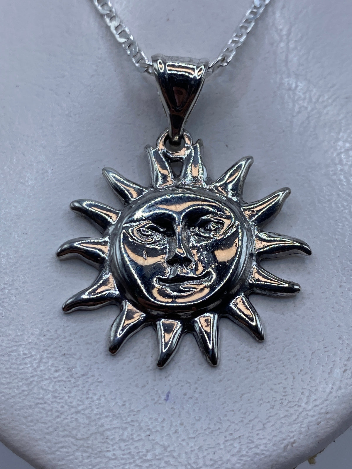 Dije de plata .925 en forma de sol sonriente con rayas puntiagudas, colgado de cadena plata en el pecho