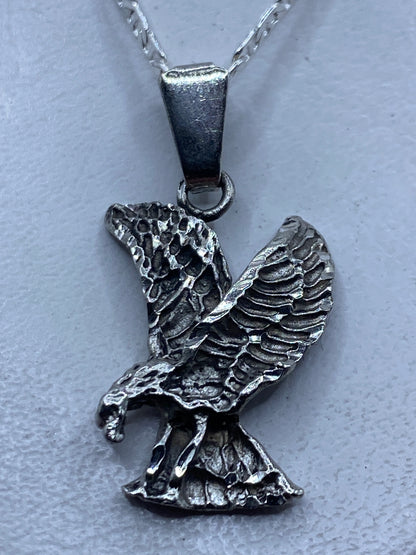 Dije águila de plata .925 en relieve repujado, vista frontal sobre fondo blanco