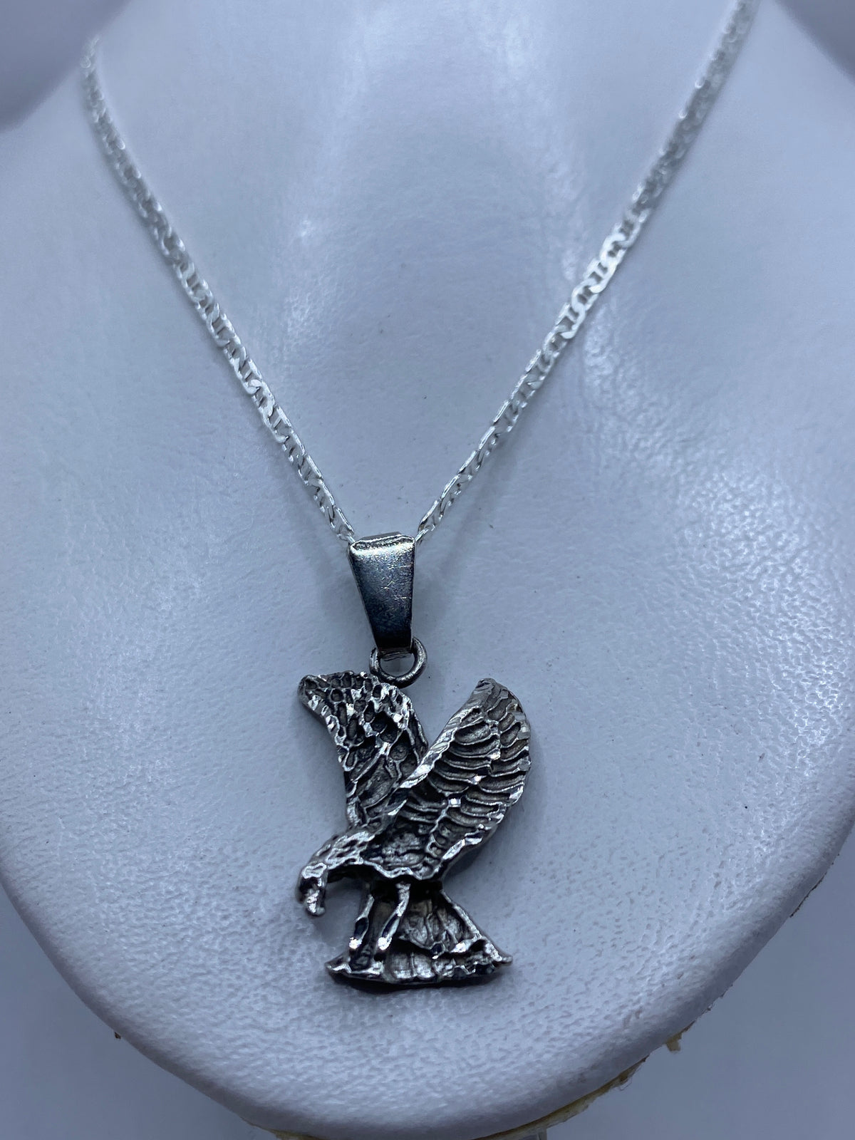 Dije águila de plata colgado en cadena plateada, vista en el pecho