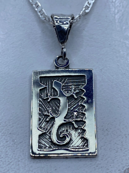 Dije prehispánico en plata repujada mostrando motivos aztecas y líneas ancestrales
