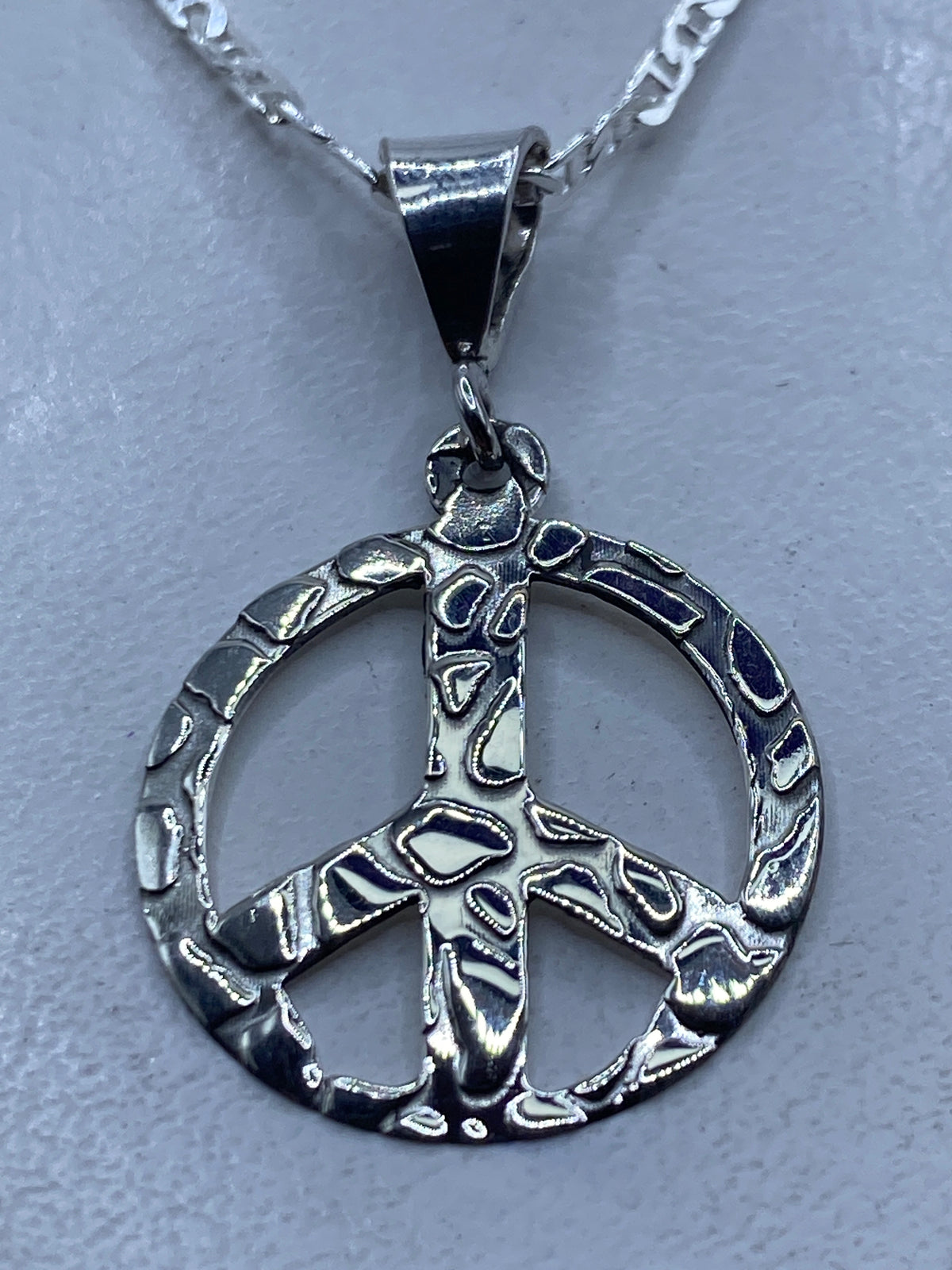 Dije símbolo de paz calado en plata .925 sobre fondo blanco