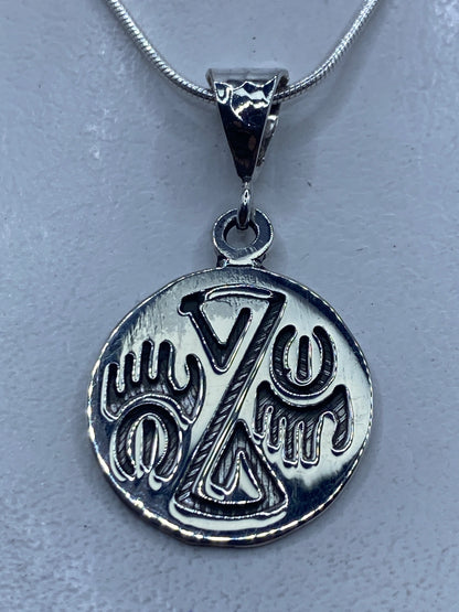 Dije de plata repujado con diseño prehispánico en mano
