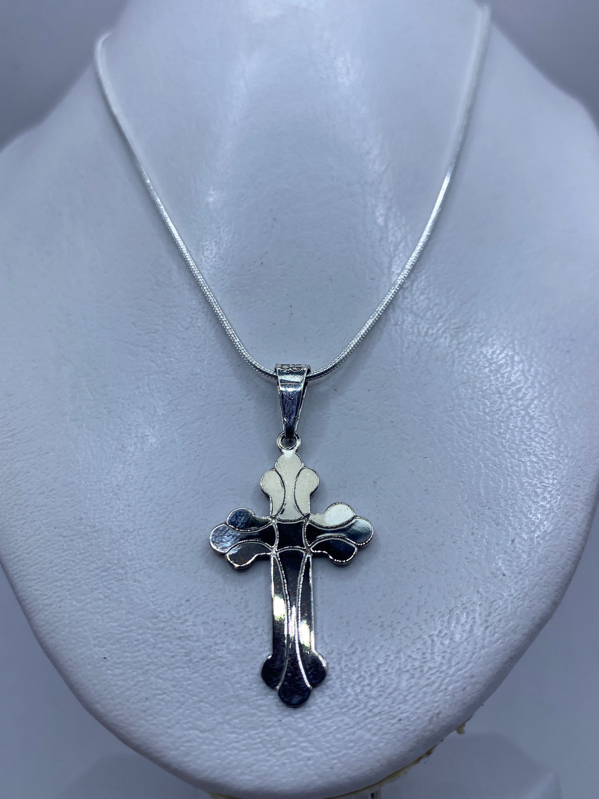 Cruz de plata fundida mostrando el acabado brillante y detalles texturizados