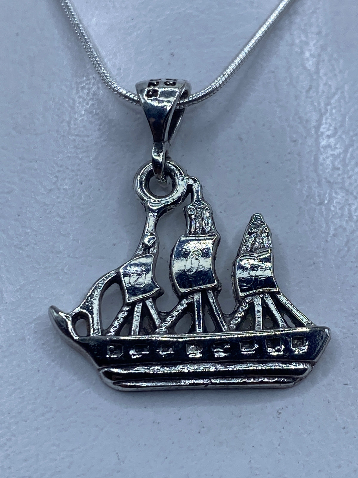 Dije de plata calado en forma de velero de tres velas, colgando de cadena de plata