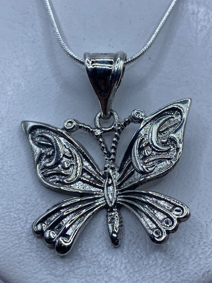 Dije de mariposa en plata repujada, 4 cm de largo, colgando de una cadena fina