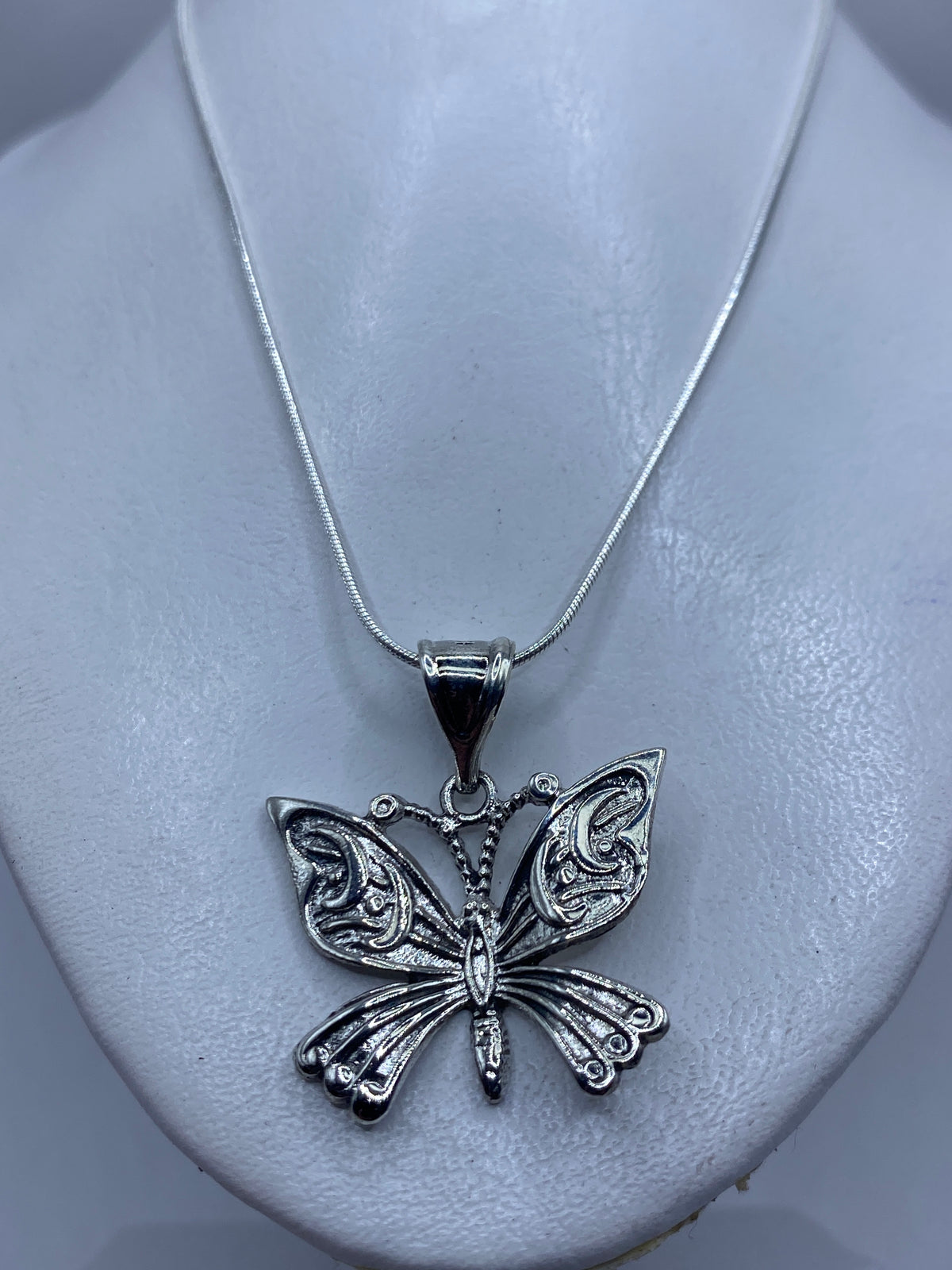 Vista lateral del dije mariposa sobre regla métrica midiendo 4 cm