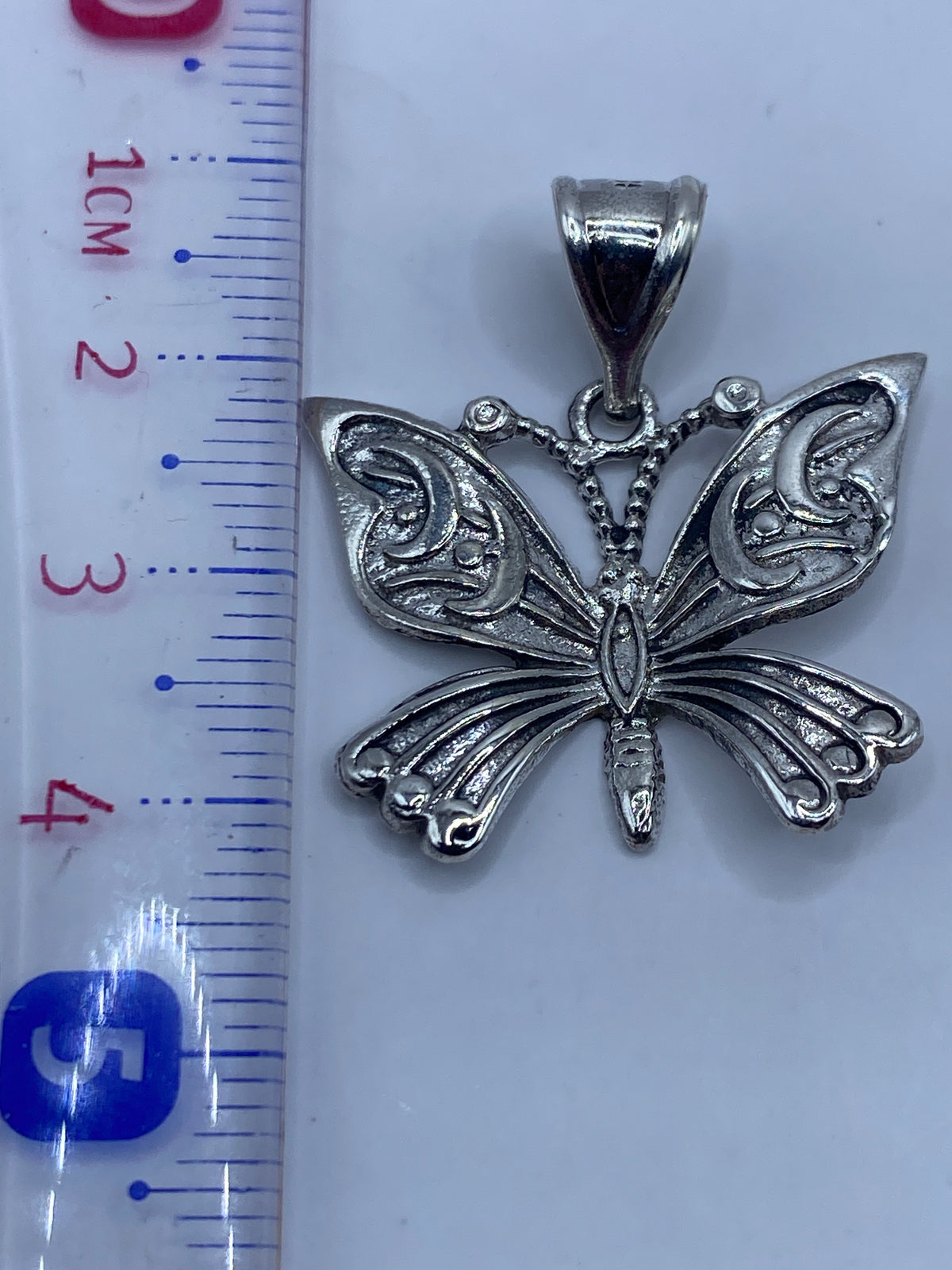 Dije mariposa en plata .925 sobre fondo blanco, vista desde atrás mostrando los detalles del cuerpo