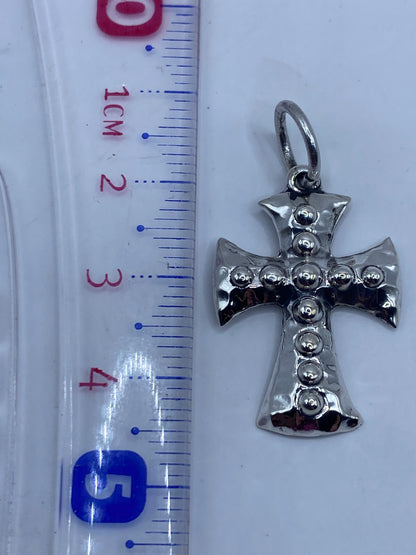 Dije cruz de plata sobre fondo blanco mostrando la textura y el Quinto .925