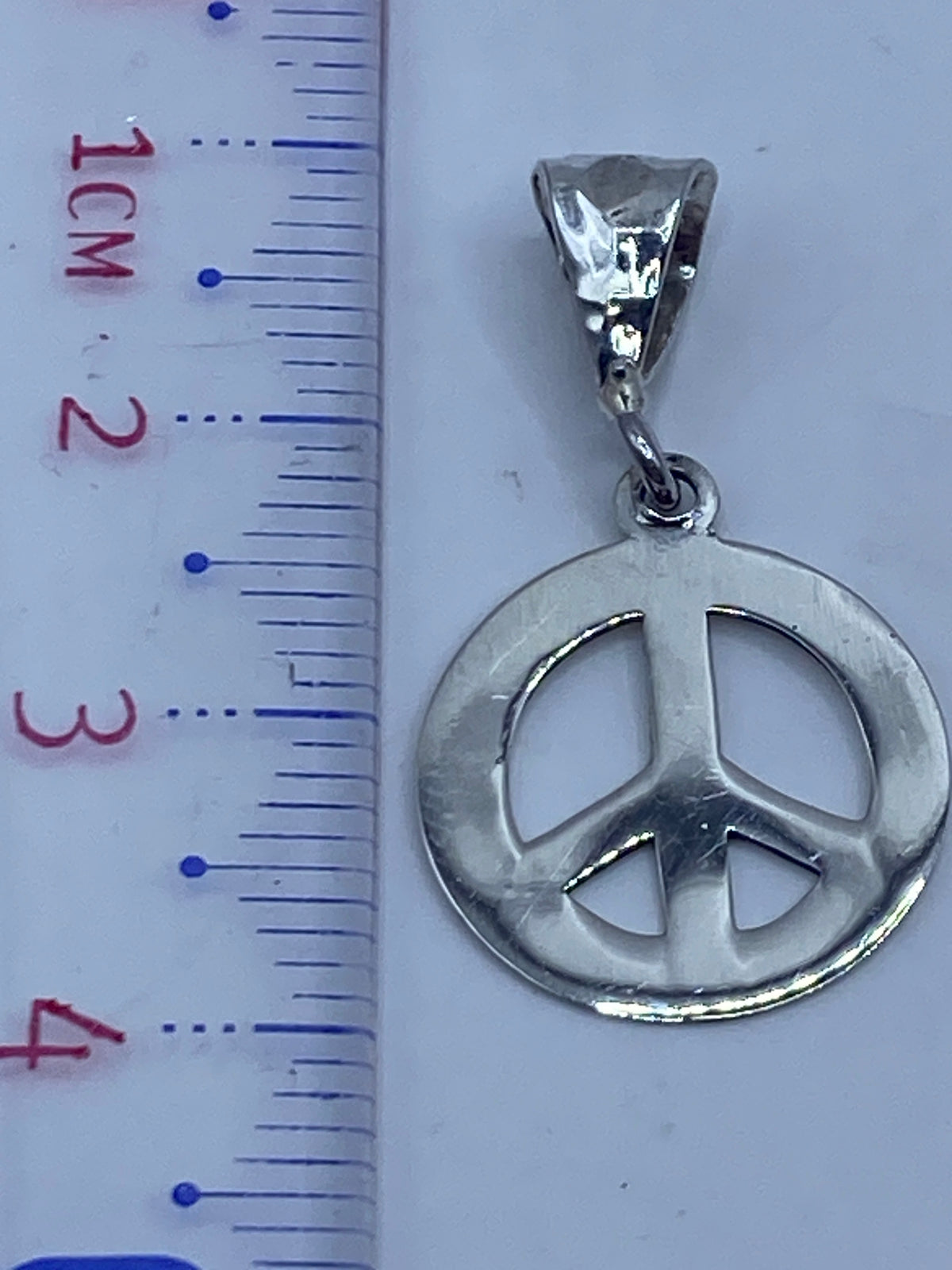 Dije de paz en escala, midiendo 3.7 cm sobre regla