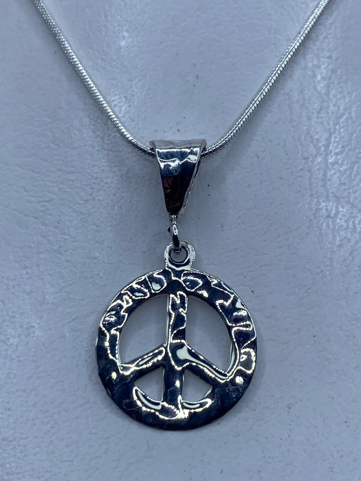 Dije de paz en plata repujada de Taxco .925, 3.7 cm, colgando de cadena plateada