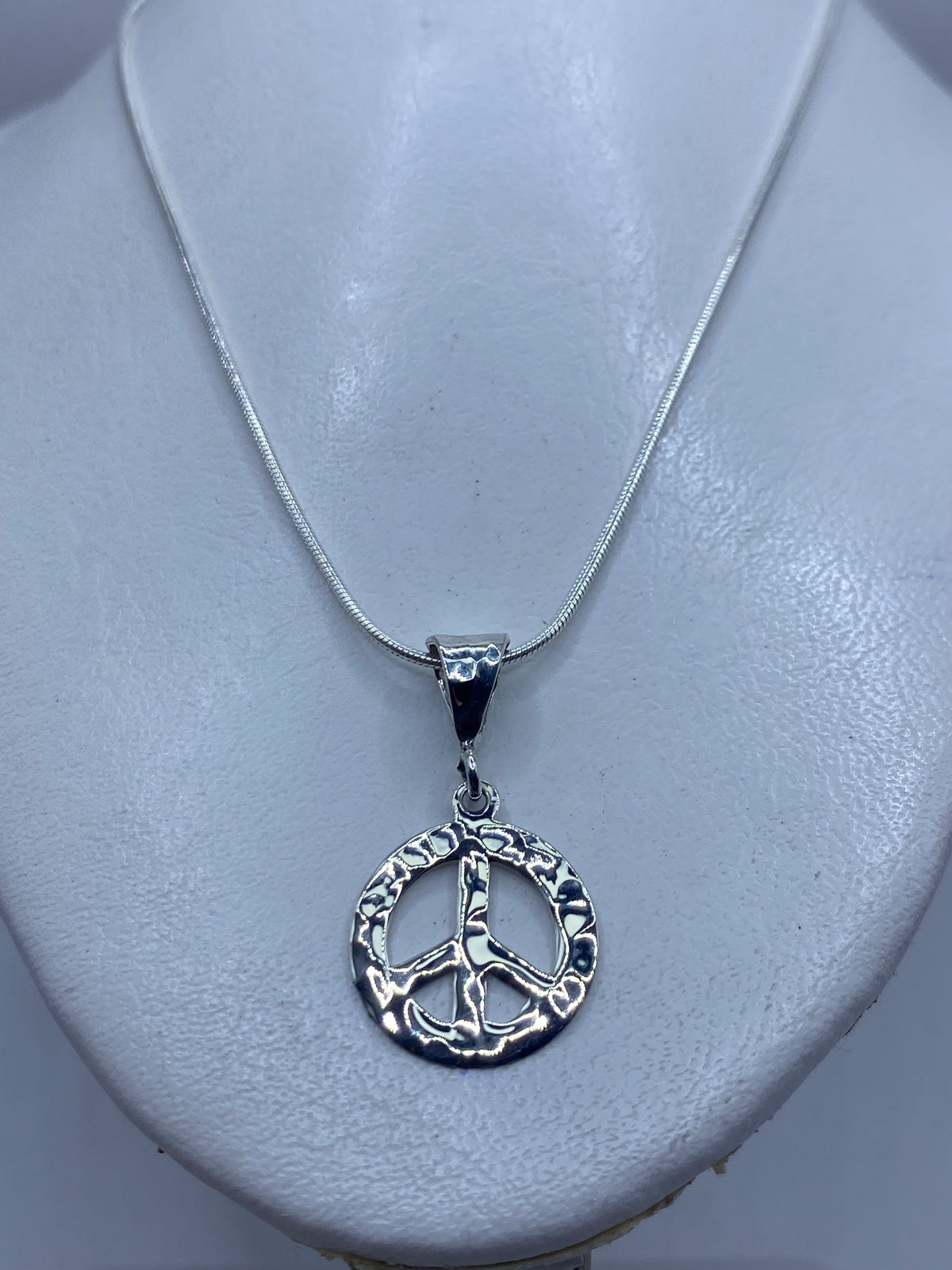 Detalle del símbolo de paz en relieve, repujado a mano en plata .925